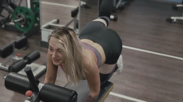 Ισχυρή κορίτσι κάνει άσκηση για τους μύες των ποδιών στο αθλητικό κέντρο σε αργή κίνηση — Αρχείο Βίντεο