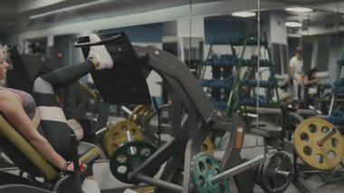 Güçlü kız spor eğitim cihazları, spor salonunda bacaklar için egzersiz yapıyor