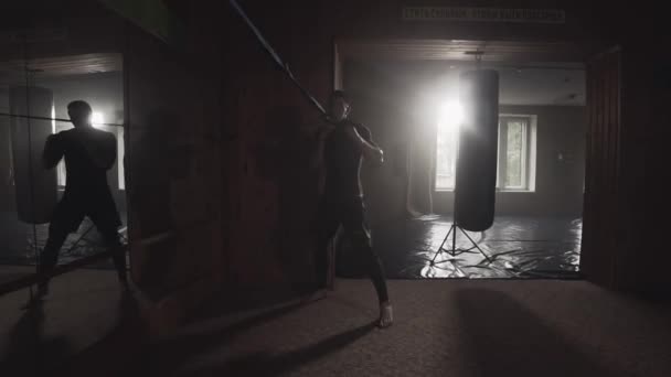 Молодой человек практикует удары в боксёрском зале — стоковое видео