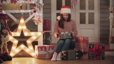 Çekici kız evi sundurma oturup Noel hediyeleri kaydırma santa şapkalı