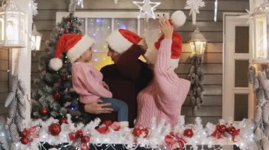 Pullovers şapka Noel sundurma sarılma, mutlu bir aile. Yeni yıl ağacı