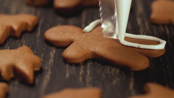 Κοντινό πλάνο γαρνίρισμα μελόψωμο ανδρών. Διαδικασία διακόσμησης χριστουγεννιάτικα μπισκότα. — Αρχείο Βίντεο