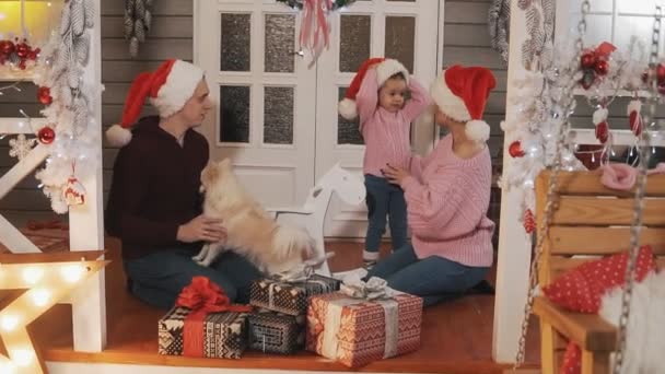 Regalos de paquete familiar para Navidad. Familia sonriendo en el porche con la decoración de Navidad — Vídeo de stock