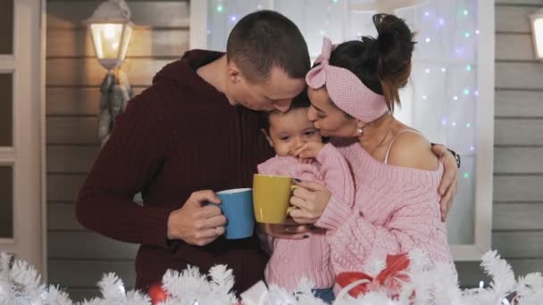 Medium shot of happy family hugging at Christmas porch with hot chocolate — Stock Video