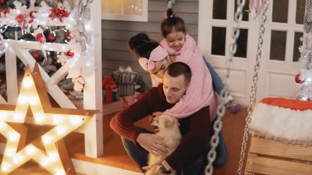 Boldog család anya, apa, lánya és kutya szórakozni a tornácon karácsony