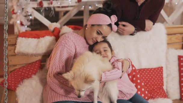 Giovane famiglia in pullover con cane seduto alla panchina di Natale al portico in slo-mo — Video Stock