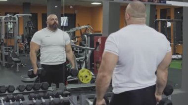 Spor salonunda dumbbells ile omuz egzersizleri performans adam. Spor kavramı
