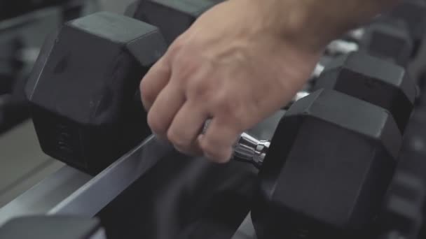 Close-up van mannenhand nemen halters, apparatuur van de opleiding van de sterkte in de sportschool — Stockvideo