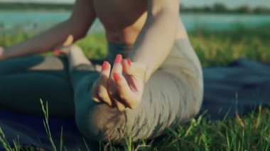 Kadın gün batımında lotus pozisyonda elleri. Gölde akşam yoga yaparken kız