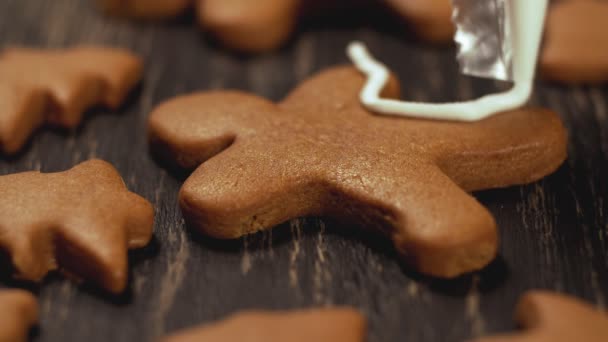 クリスマスのクッキーの装飾のプロセス。クローズ アップ ジンジャーブレッド人を飾り — ストック動画