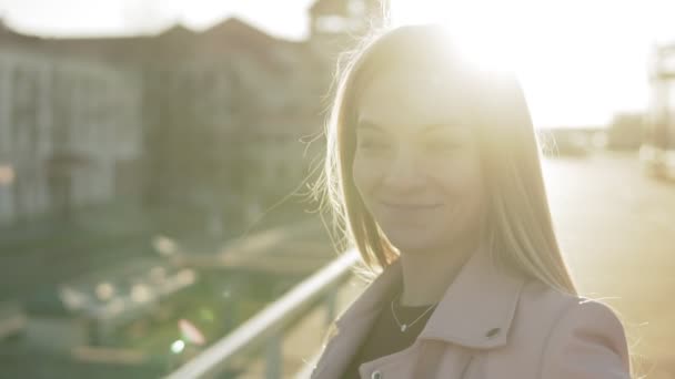 Close-up Portrait of pretty woman with long hair smiling in city at sunrise — Stock Video