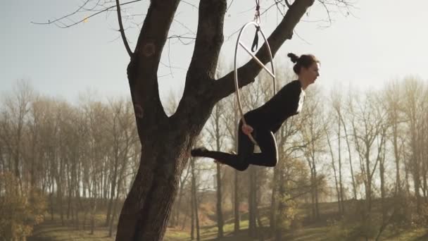 Young woman doing some acrobatic elements on aerial hoop outdoors in slow-mo — Stock Video