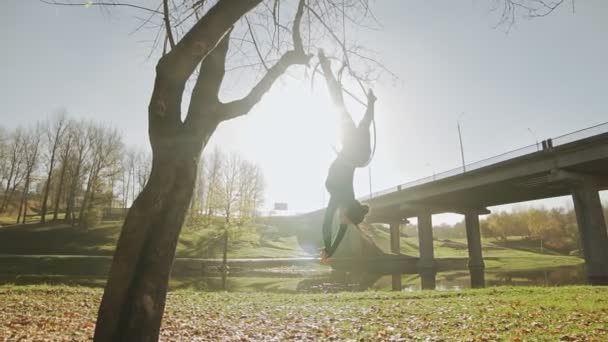 Flexible Brünette hängt im Ring für Luftakrobatik bei Sonnenaufgang in Zeitlupe — Stockvideo