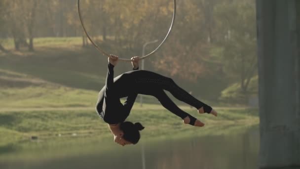 Vrouw doen sommige acrobatische elementen op luchtfoto hoepel buitenshuis. Flexibele meisje — Stockvideo