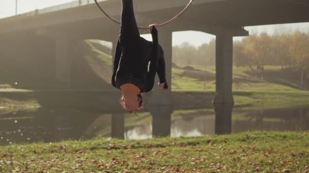 Mujer flexible haciendo elementos acrobáticos en aro aéreo. Morena colgando en el anillo — Vídeos de Stock