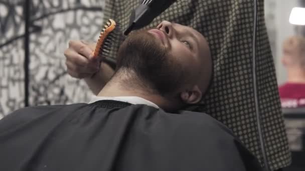 Nahaufnahme eines männlichen Barbiers, der Bart mit Rasierapparat trimmt. professionelle Rasur — Stockvideo
