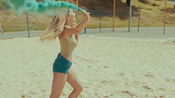 Joyeuses filles hipster en short court dans le champ de sable agitant la fumée colorée et sauter — Video