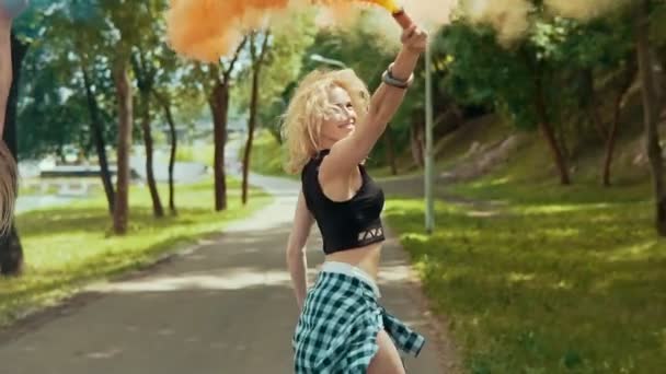 Muito hipster meninas em roupas bonitas corre no parque acenando fumaça colorida — Vídeo de Stock