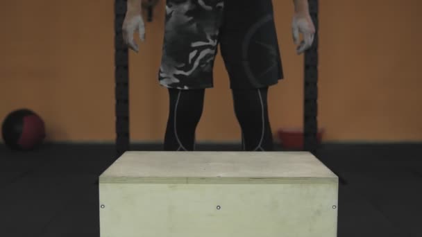 Primer plano del hombre saltando en cubo de madera en el gimnasio. Hombre en forma haciendo saltos de caja — Vídeos de Stock