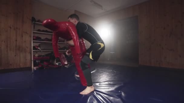 Jeune homme pratiquant avec sac de boxe factice dans la salle de gym au ralenti — Video