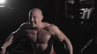 Erkek vücut geliştirmeci eğitim göğüs kasları egzersiz vücut için makine üzerinde çapraz kablo kullanma kitle. Adam yavaş hareket çeker ağırlık egzersiz yaparak koyu spor salonunda. Egzersiz ve vücut geliştirme sporu kavramı