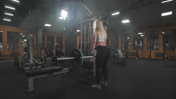 Σέξι ξανθιά γυναίκα στο γυμναστήριο κάνοντας ασκήσεις σε στάση οκλαδόν με barbell σε αργή κίνηση — Αρχείο Βίντεο