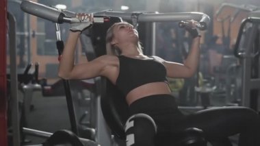 Spor salonunda fitness egzersiz donanımları üzerinde çalışan atletik genç kadın