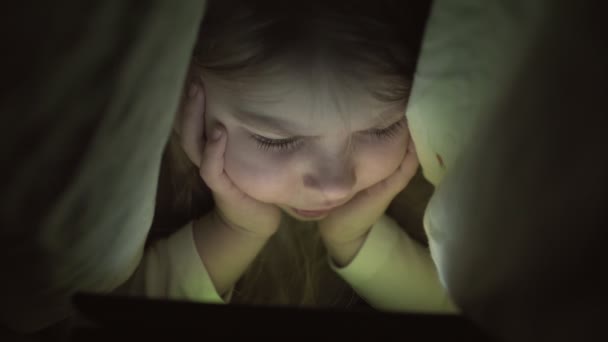 Malá holčička s tabletem pod dekou. Dítě v noci s tabletem — Stock video