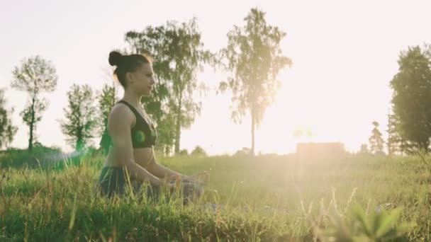 Красива дівчина в позі лотоса на сході сонця. Здоровий спосіб життя та концепція йоги — стокове відео