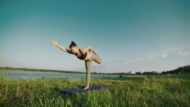 Vacker flicka gör yoga utomhus vid soluppgången. Fitness girl utbildning i morgon — Stockvideo