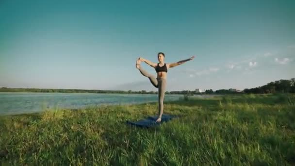 Dívka v ráno. Hezká holka dělá jógu a pilates venkovní při východu slunce — Stock video