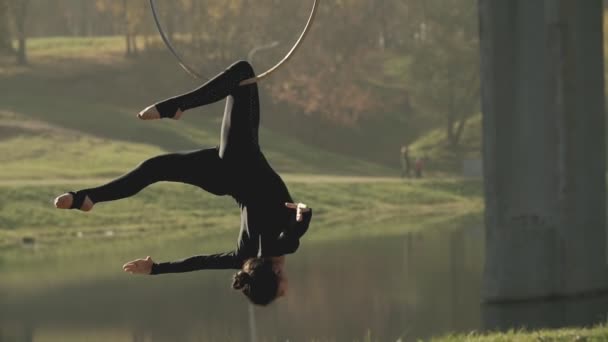 Mujer gimnasia aérea realiza acrobacias truco en aro aéreo. Morena flexible — Vídeos de Stock