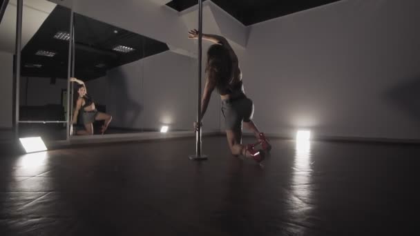 Жінка з сексуальною формою танцює біля полюса в повільному русі. Танцівниця рухається — стокове відео