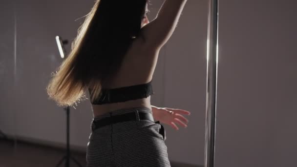 Primer plano de una joven mujer bailando en un estudio oscuro. Mujer bailando cerca de polo — Vídeo de stock