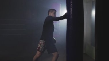 Muay Tay savaşçı dumanlı Studio'da Delme. Kick boks kum torbası ile eğitim