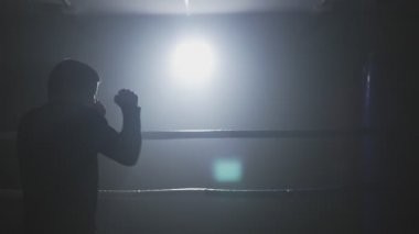 Düşük ışık ringde eğitim kick boks şampiyonu. Siluet koyu arka plan üzerinde