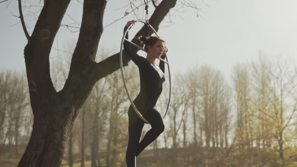 Young woman doing some acrobatic elements on aerial hoop outdoors in slow-mo — Stock Video