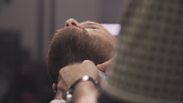 Barber shaving beard with electric razor. Close up of male barber trimming beard — Stock Video