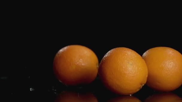 Pomalý pohyb pomerančů padajících do vody na tmavém pozadí s prostorem pro kopírování — Stock video
