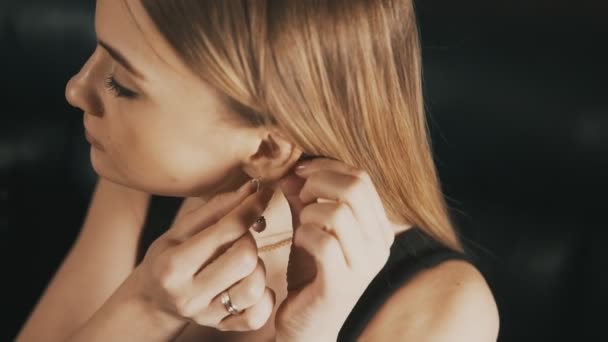 Beautiful woman puts on beautiful earrings. Close up — Stock Video