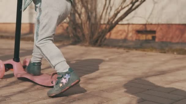Glückliches Mädchen fährt auf rosa Roller im Freien bei sonnigem Tag in Slomo mit Copyspace — Stockvideo