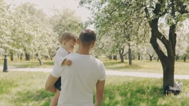 Отец и сын гуляют в парке. Молодой отец и маленький сын веселятся на открытом воздухе — стоковое видео