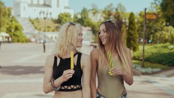 Beautiful women friends walking in city street eat ice cream in slow motion — Stock Video