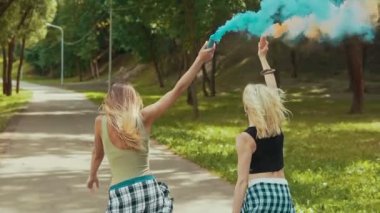 Güzel kıyafetler mutlu hipster kızlar Park renkli duman sallayarak çalışır