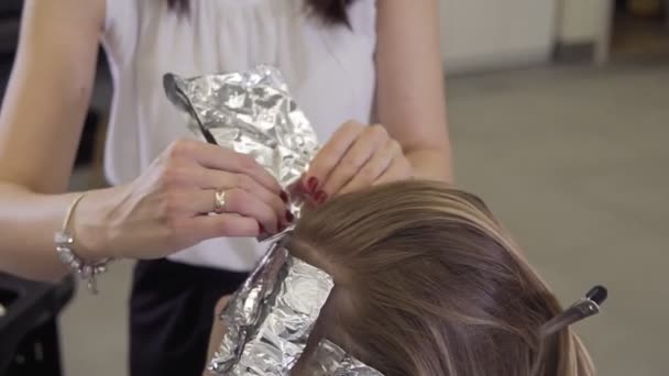 Peluquero aplicando tinte colorante para aligerar el tono del cabello . — Vídeo de stock