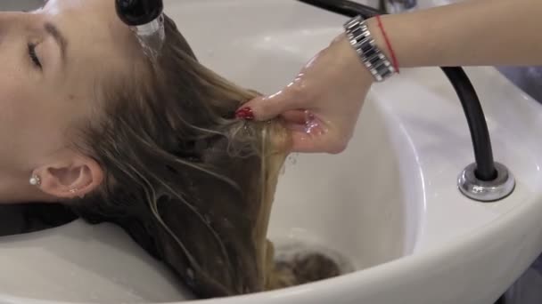 Красивая девушка моет волосы перед стрижкой в салоне красоты. Мытье волос — стоковое видео