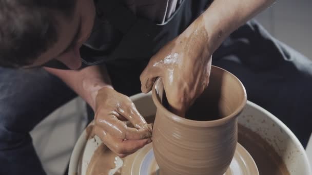 L'homme crée des produits sur la poterie de tournage de tour de potier. Les mains créent une cruche à partir d'argile — Video