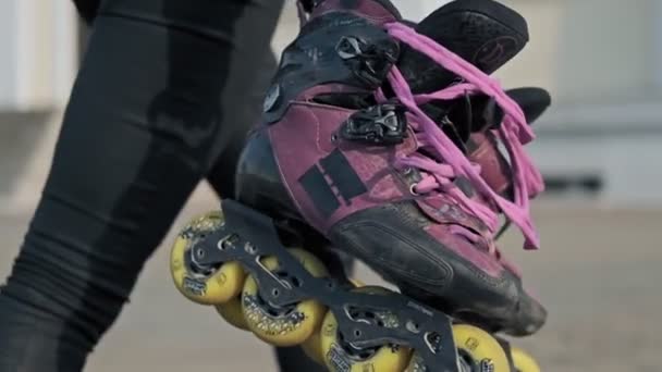 Ung kvinna gå med rollerbladen i händerna på bakgrund av gatan. Närbild — Stockvideo