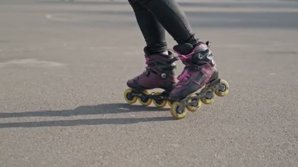 Gros plan sur les jambes balades sur patins à roulettes et tourbillon. Fille conduite patins à roulettes . — Video