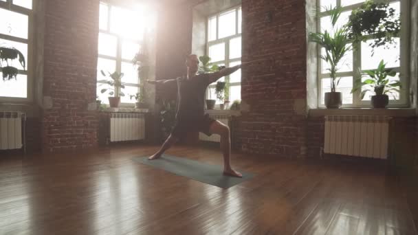 Man Practice Warrior Yoga Pose Studion Med Tegelvägg Och Solstrålar — Stockvideo